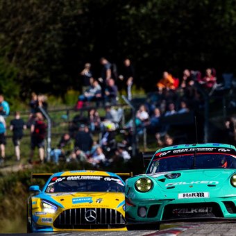 Rennwagen auf der Nordschleife bei der ADAC Nürburgring Langstrecken-Serie mit jubelnden Fans am Streckenrand.