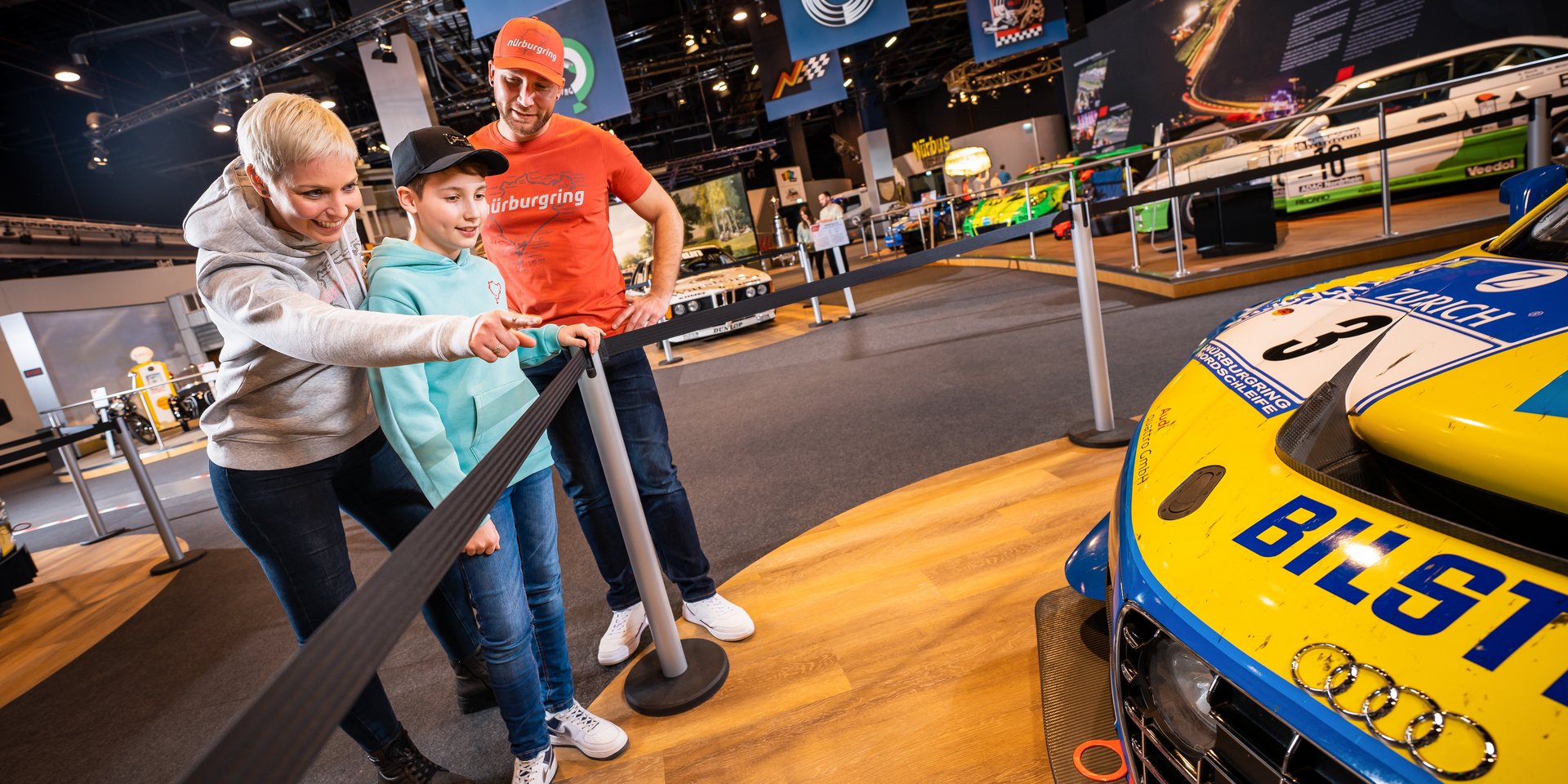 Familie entdeckt ein Rennfahrzeug in der Ausstellung des Nürburgring ring°werk.