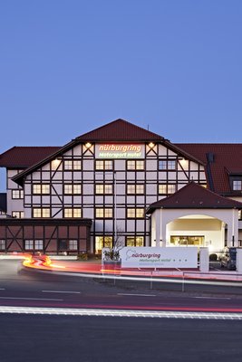 Außenansicht des Nürburgring Motorsport Hotels am Abend mit beleuchtetem Eingang